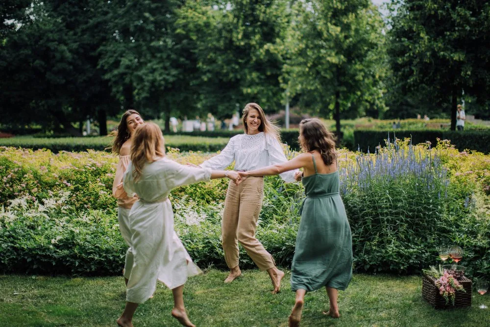 Un groupe de femmes dansant joyeusement, leurs cœurs représentés comme des orbes de lumière vibrants et pulsants, battant plus vite que ceux des hommes autour d'elles.